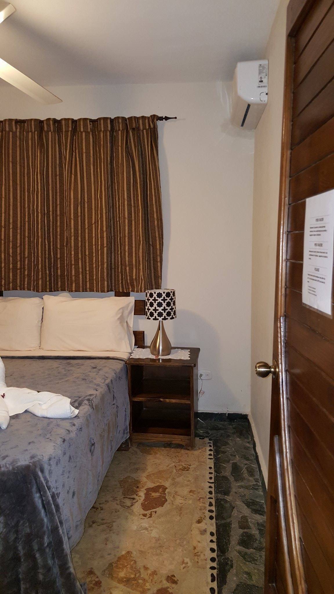 Bedroom with a bedside lamp, curtained window and air conditioner