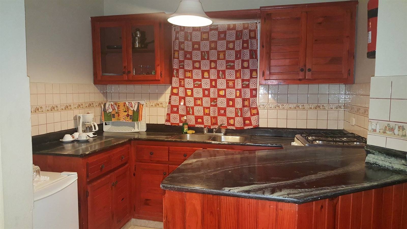 Apartment kitchen with red cabinets and a tiled backsplash